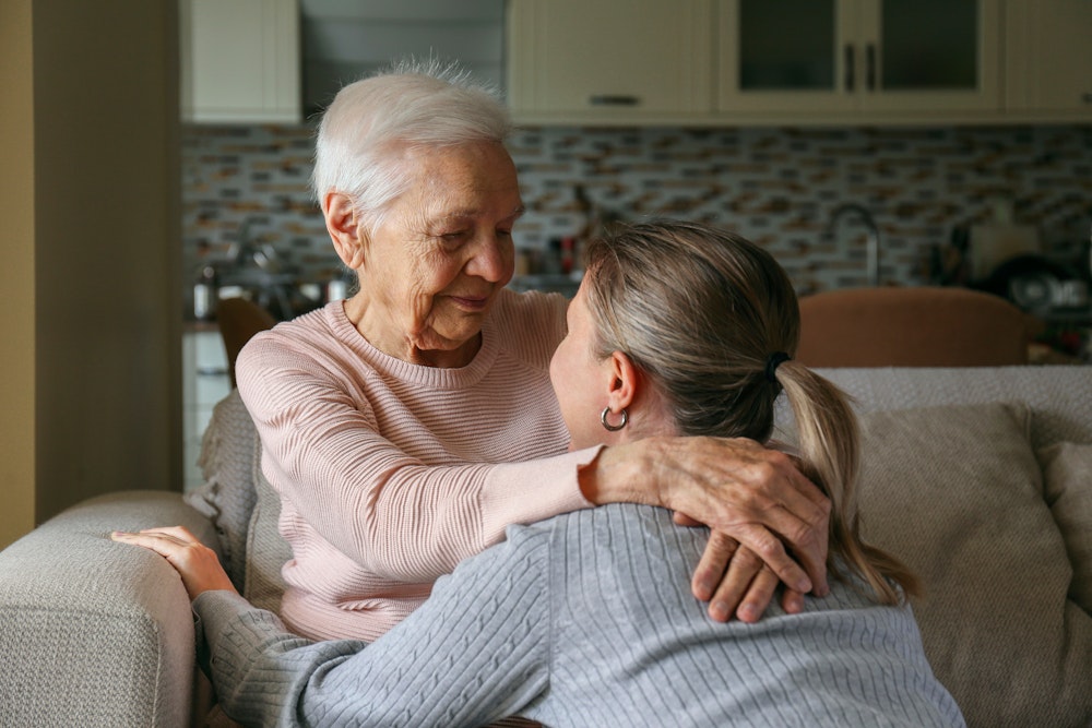 Daughter hugging elderly mother