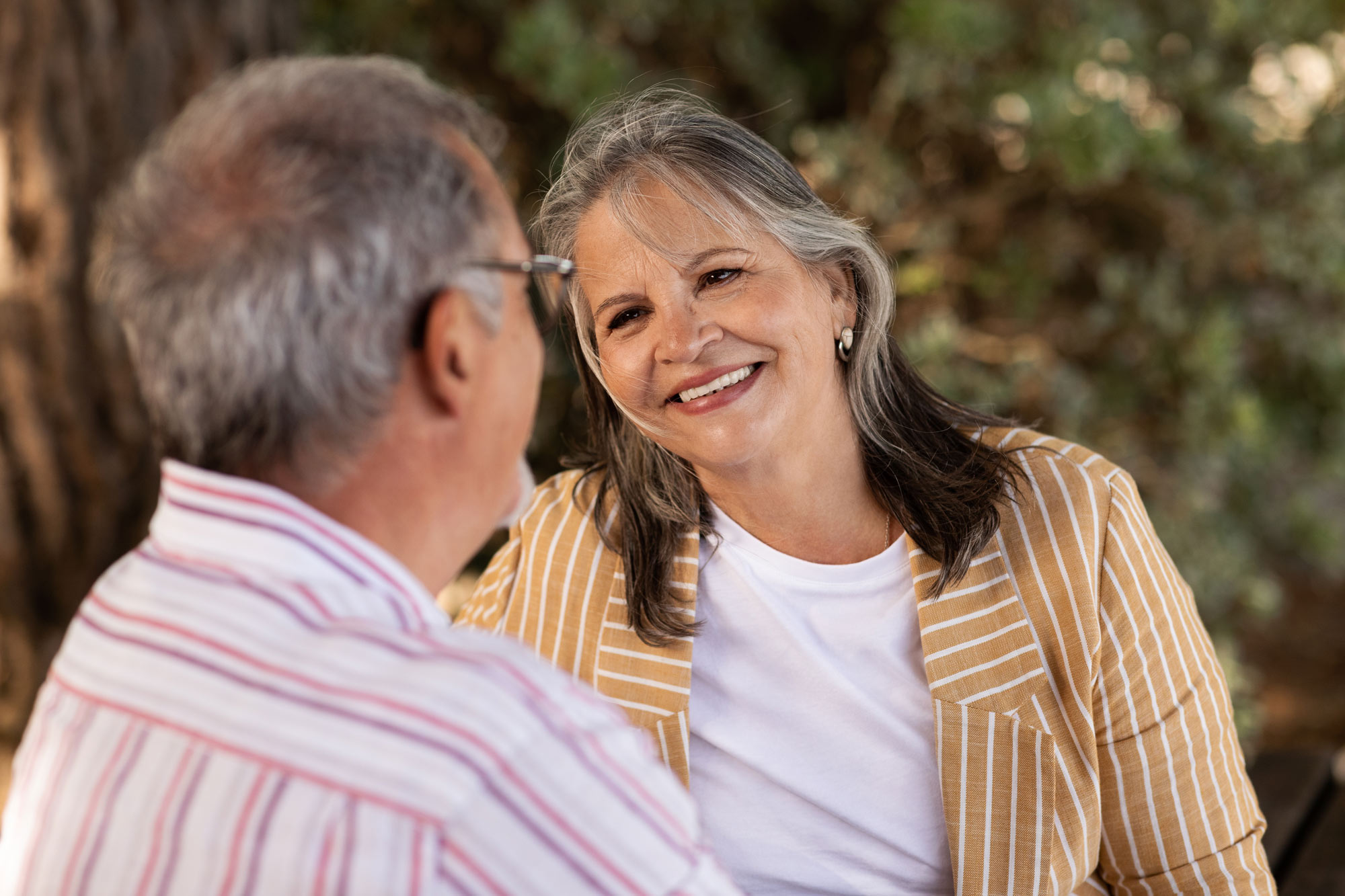 Mature woman in striped yellow shirt smiling at man