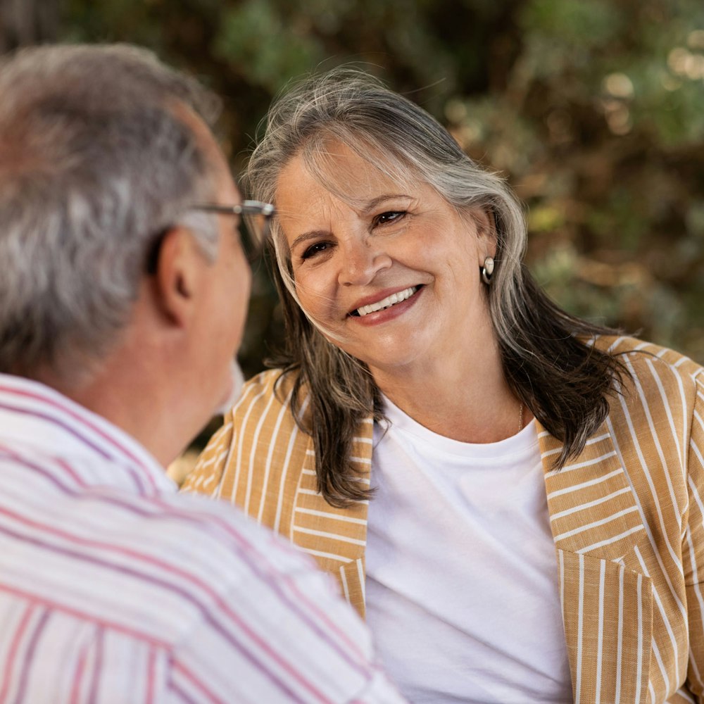 Mature woman in striped yellow shirt smiling at man