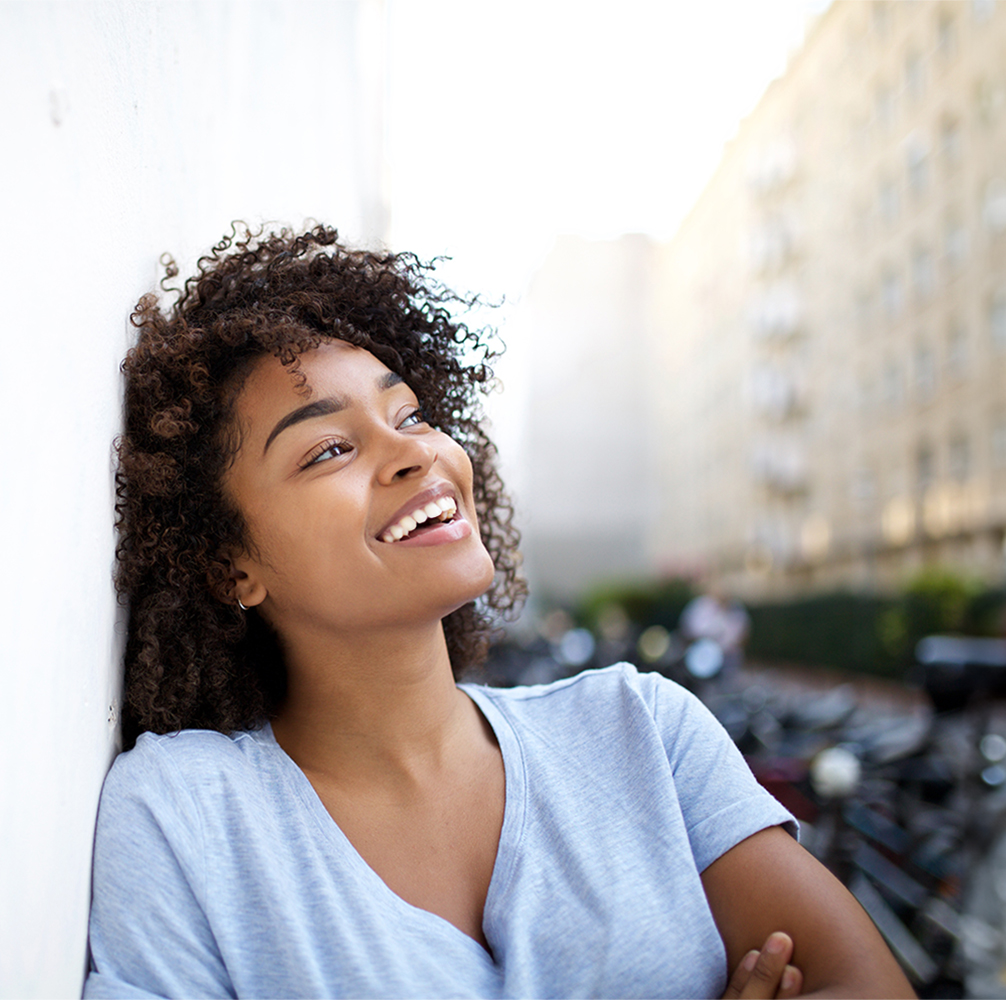 Young woman leaning against a wall smiling