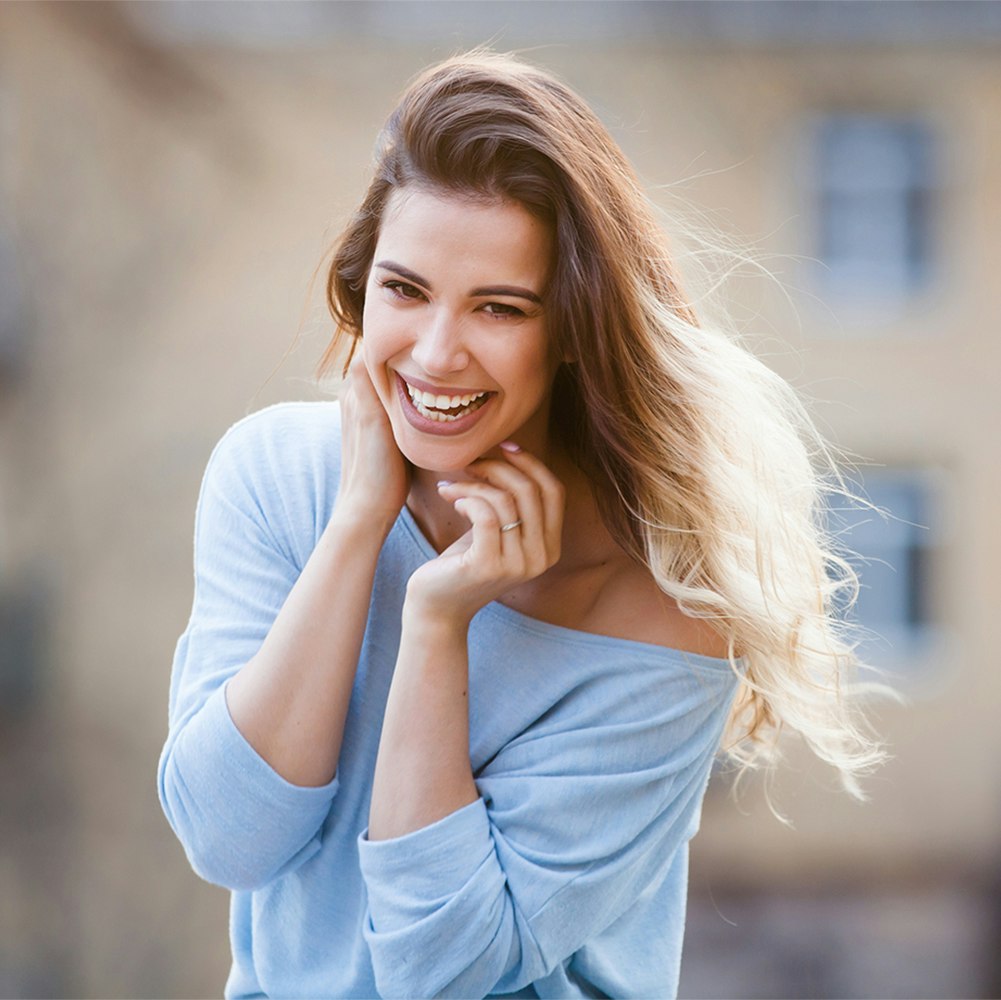 Young woman smiling while the wind blows her hair