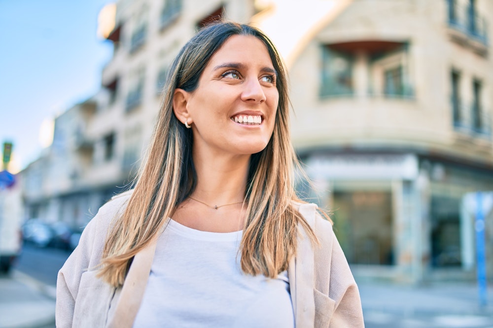 Woman flashing her restored smile while walking downtown