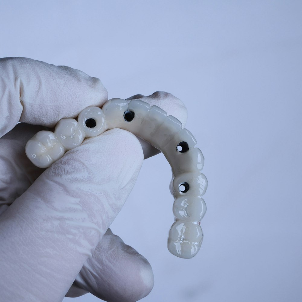 gloved hand holding all-on-4 denture
