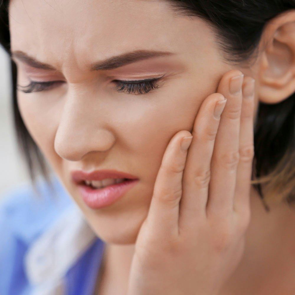 woman holding her jaw in pain