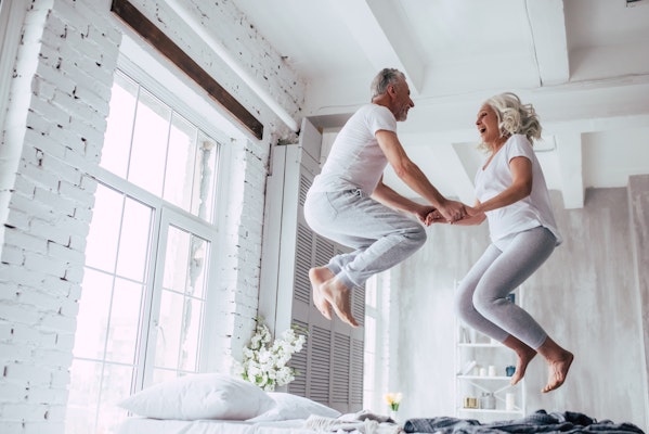 Older couple jumping on a bed