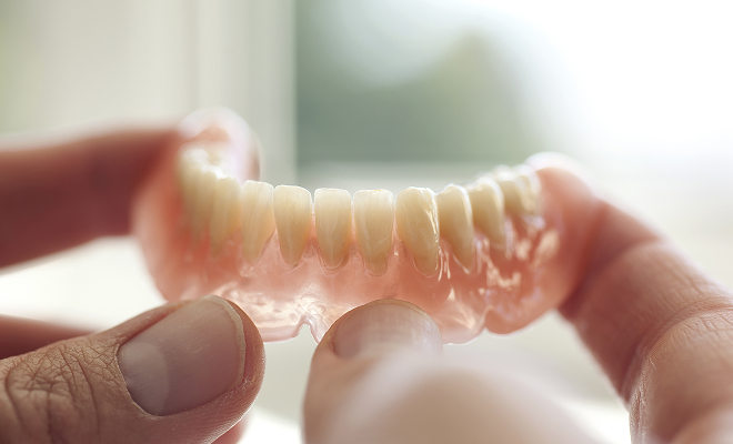 Hands holding a traditional denture