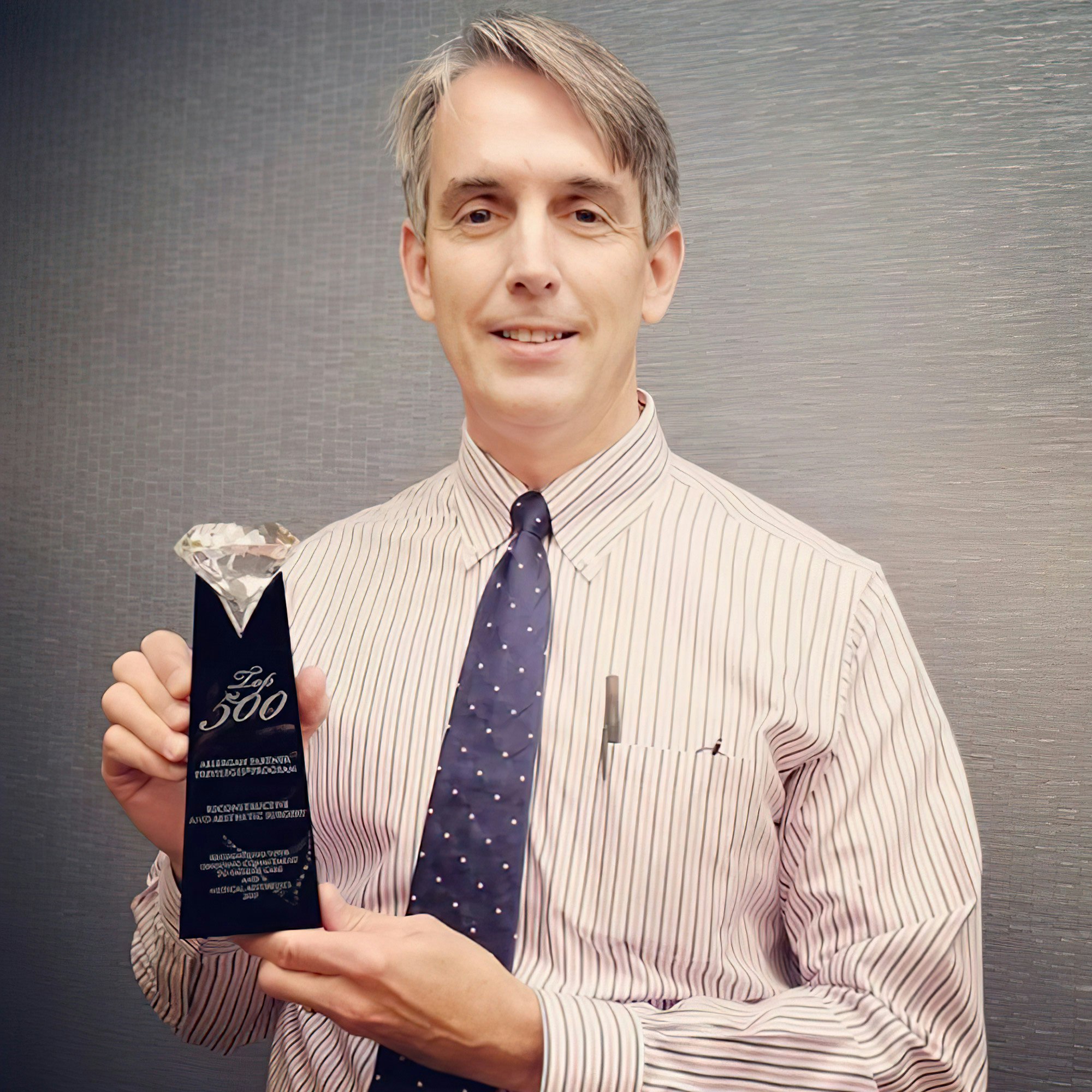 Dr. John F. Zavell holding Top 500 trophy