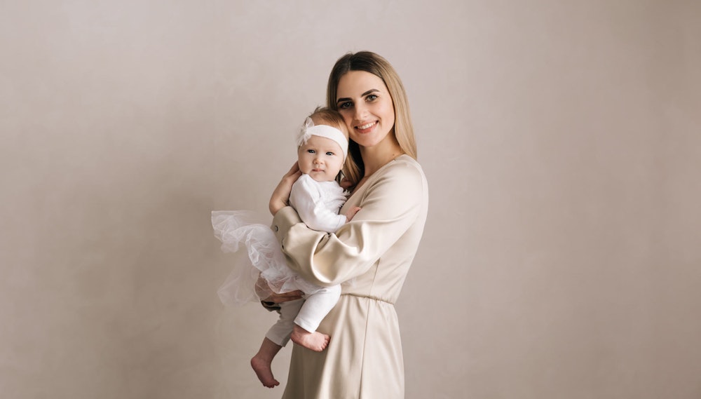 Mom holding baby after mommy makeover procedure