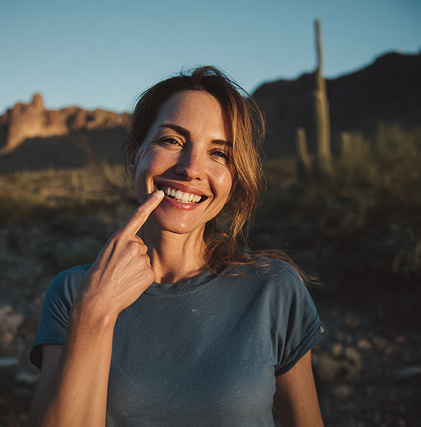 Woman pointing to tooth with AZ desert in the background