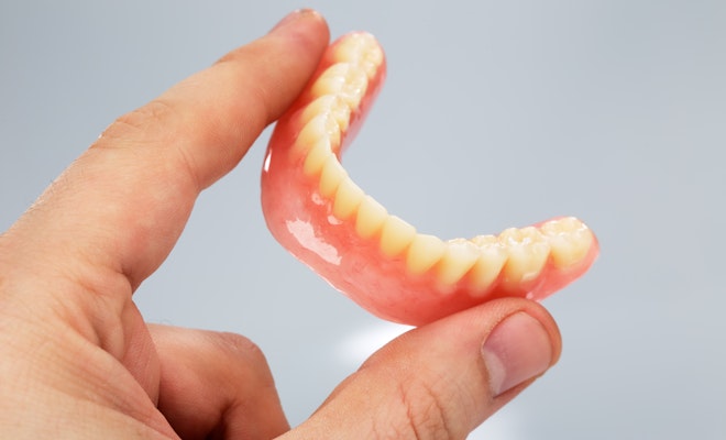 Hand holding dentures