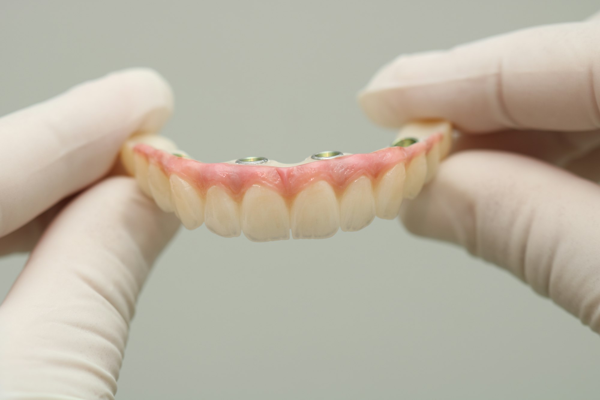 Gloved hands holding implant dentures