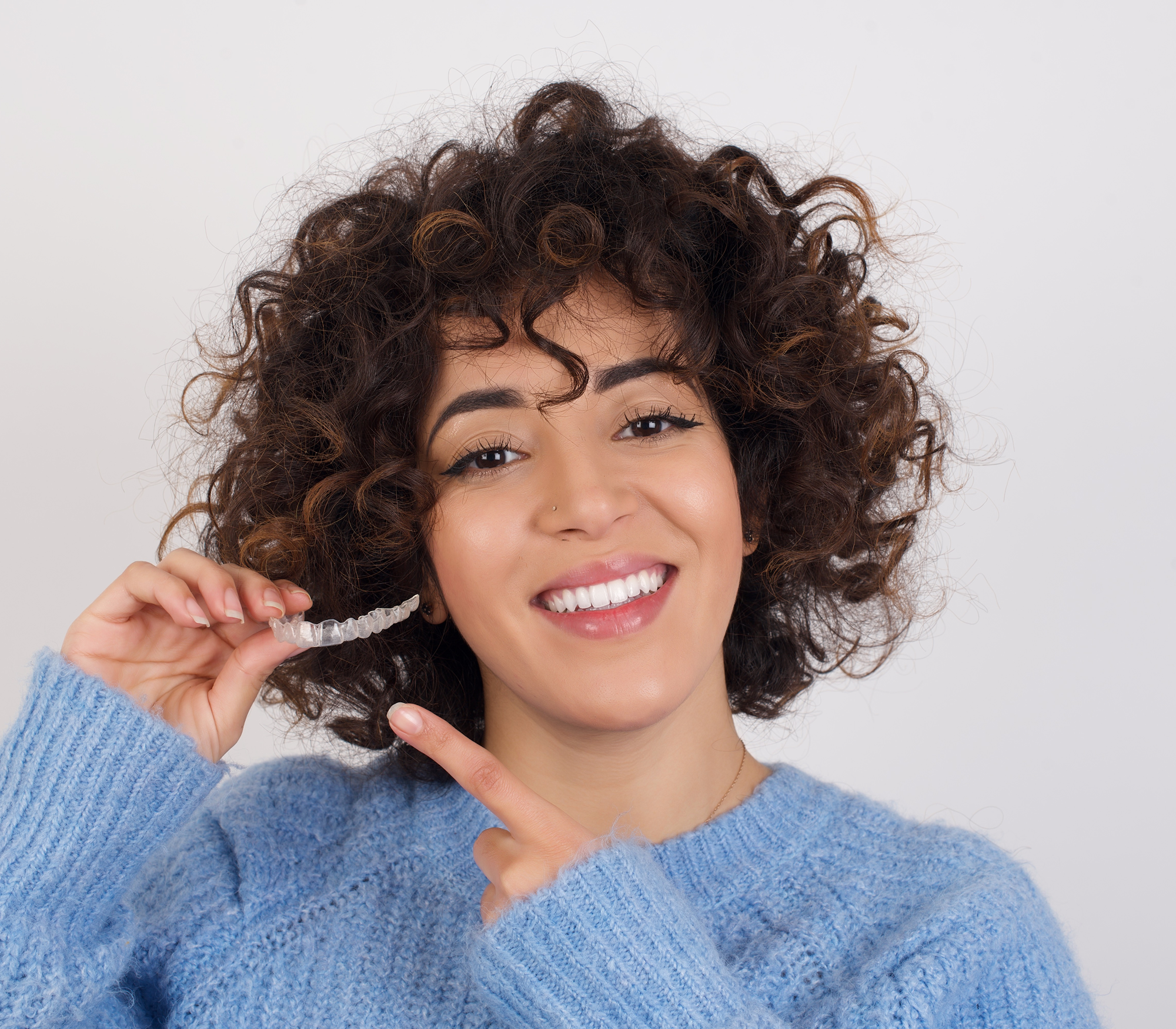 Woman smiling while holding invisalign