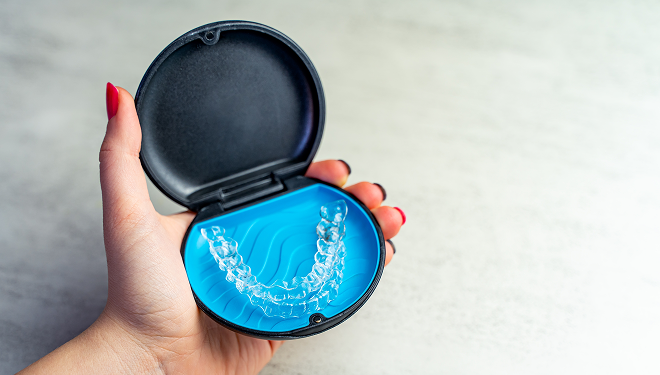 Hand holding an open Invisalign case