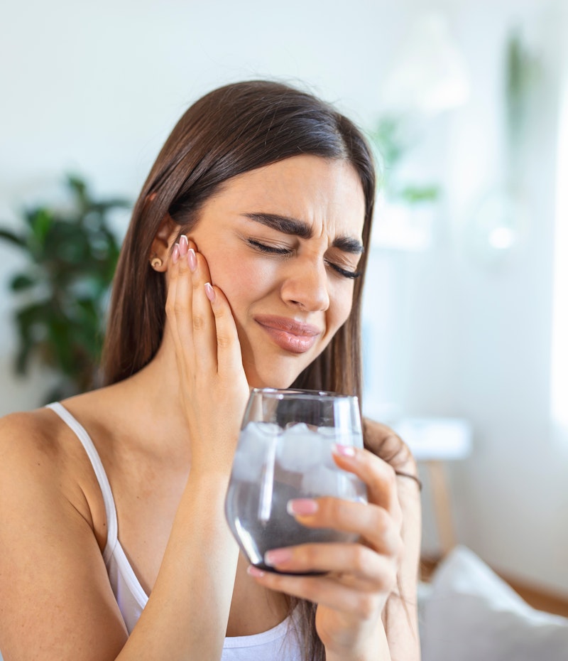 Woman with sensitive teeth drinking ice water