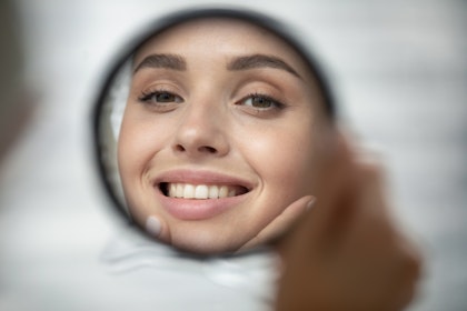 Woman smiling in mirror at the dentist