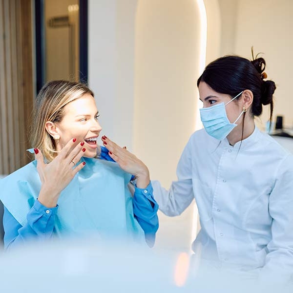Dental hygienist speaking with young patient in exam room
