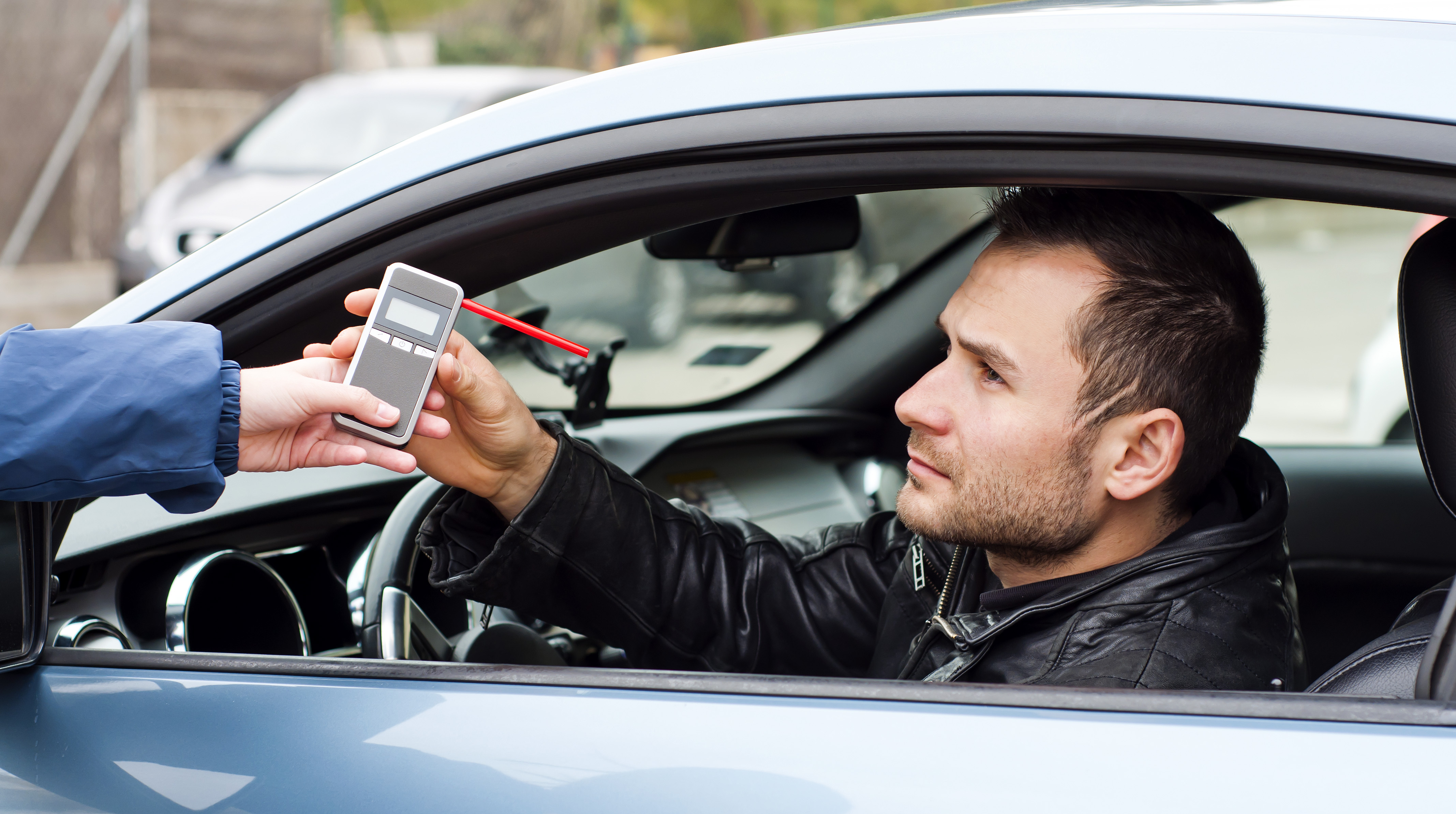 Man taking breathalyzer from cop at traffic stop