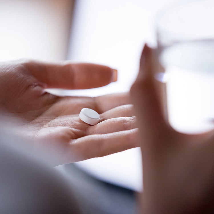 a hand holding a pill