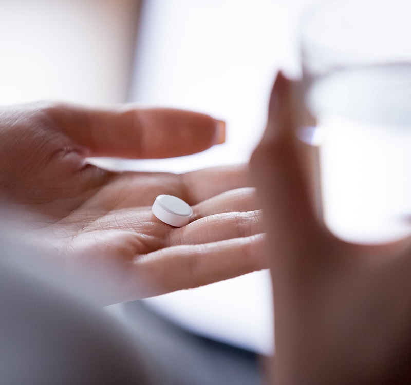 a hand holding a pill