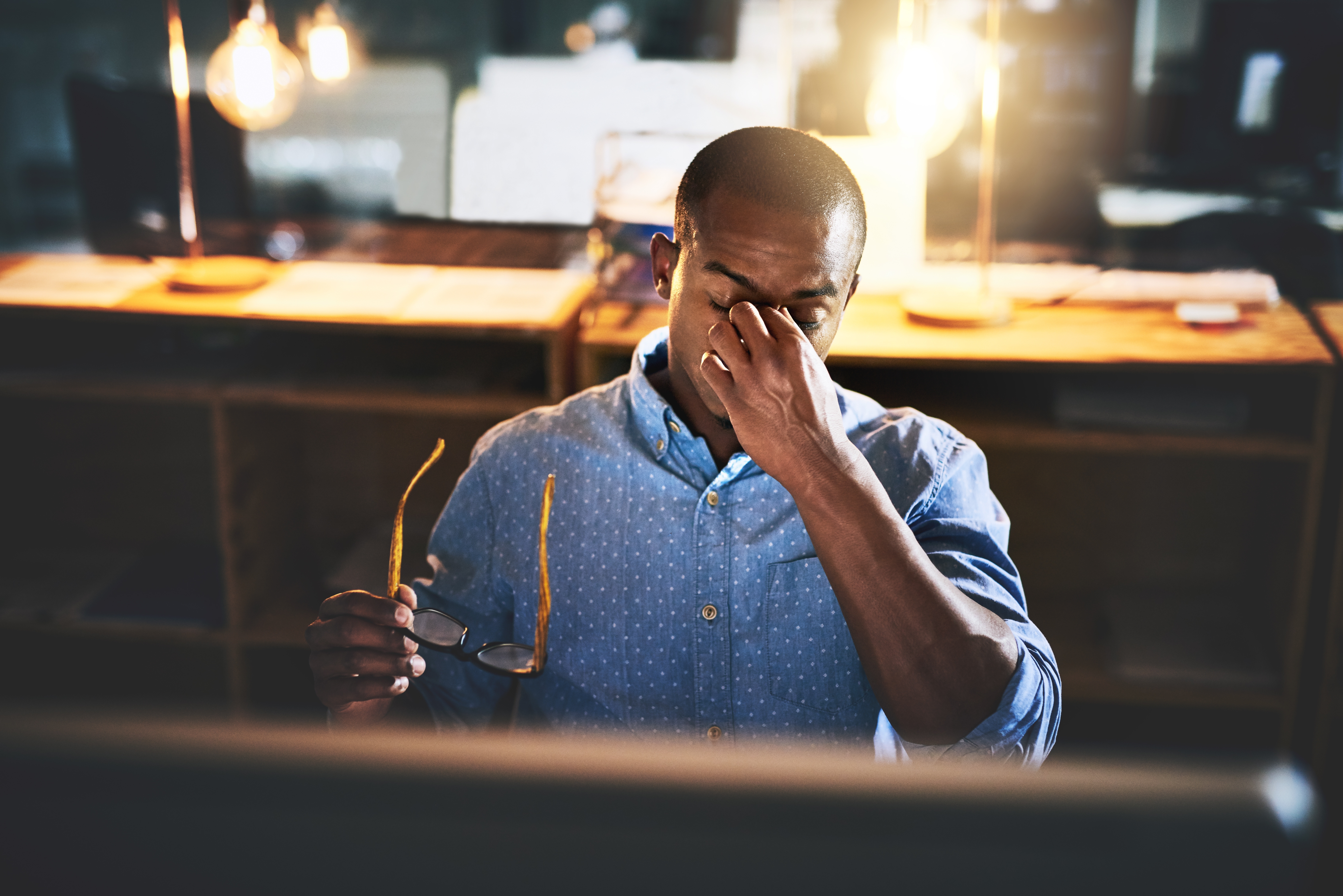 Tired worker holding glasses and rubbing the bridge of his nose