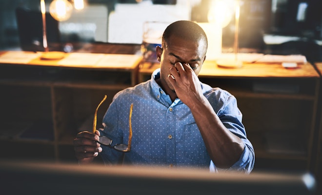 Tired worker holding glasses and rubbing the bridge of his nose