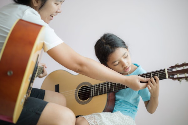 Young girl learning how to play guitar