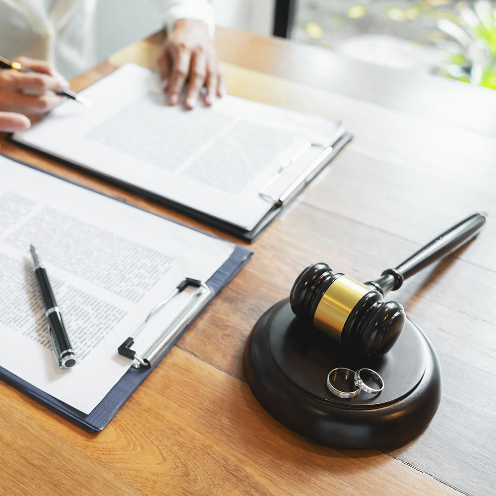 Gavel, wedding rings, and paperwork on a desk
