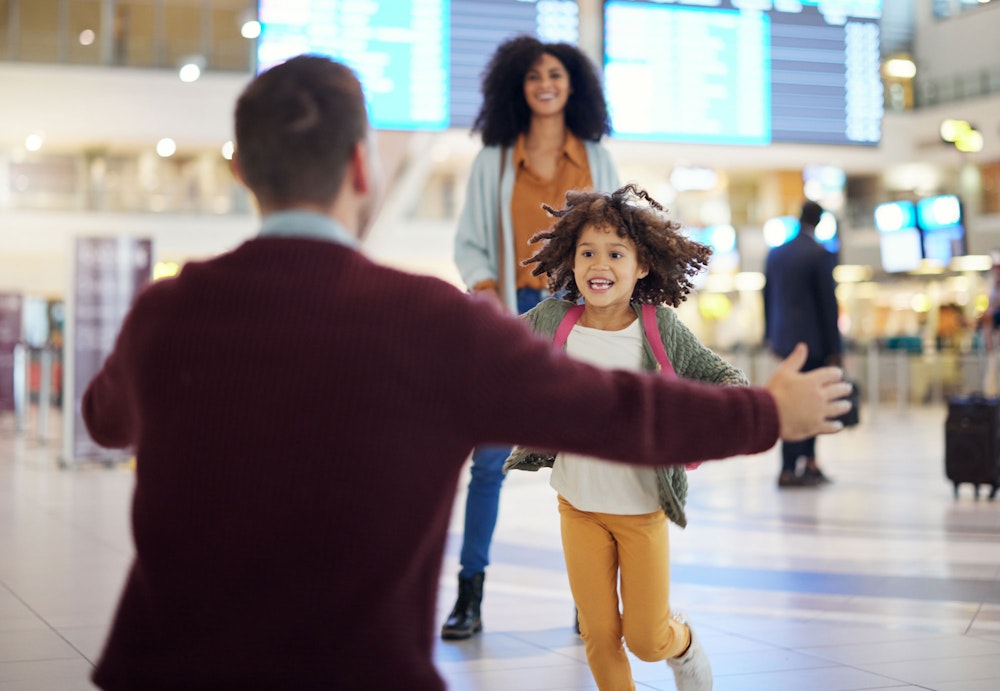 Excited girl at airport running from mother to father