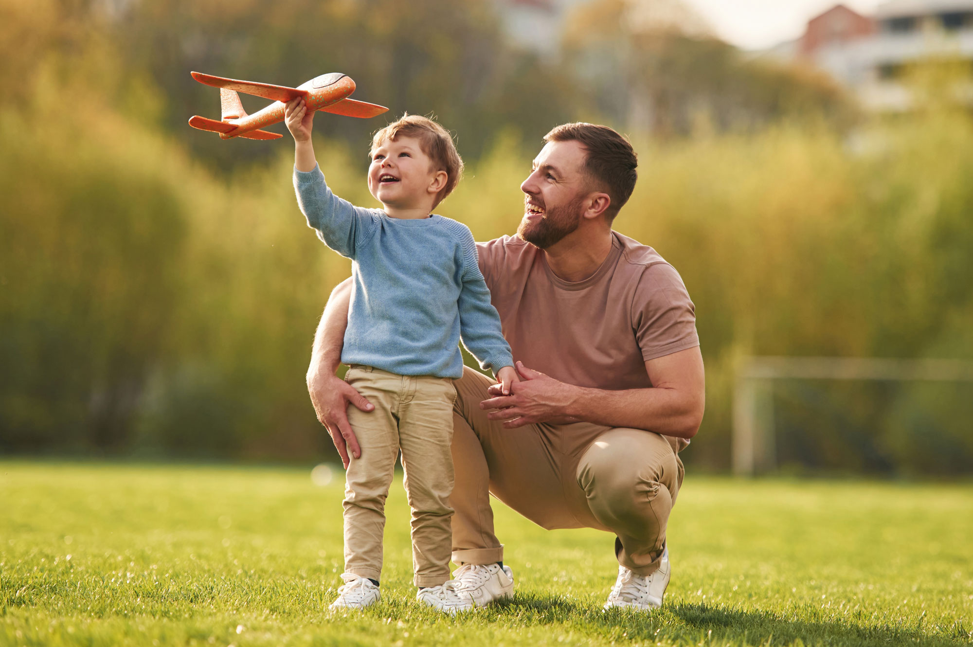 Father and son playing outside with a toy airplane