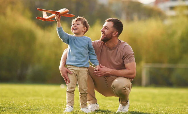 Father and son playing outside with a toy airplane