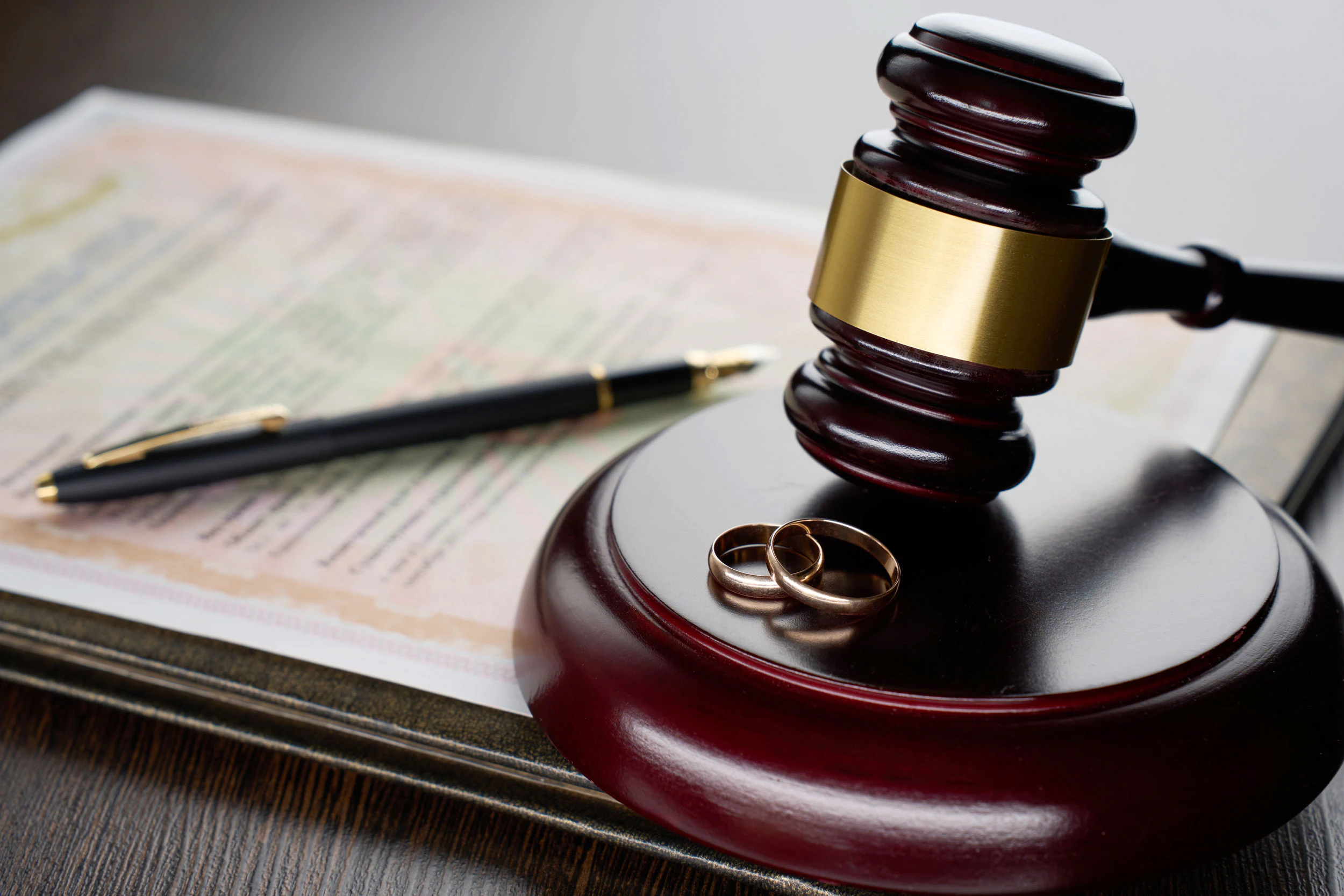 Gavel with wedding rings and a document with pen