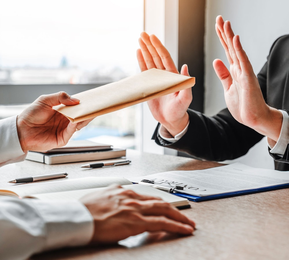 Someone refusing documents being handed to them at a desk