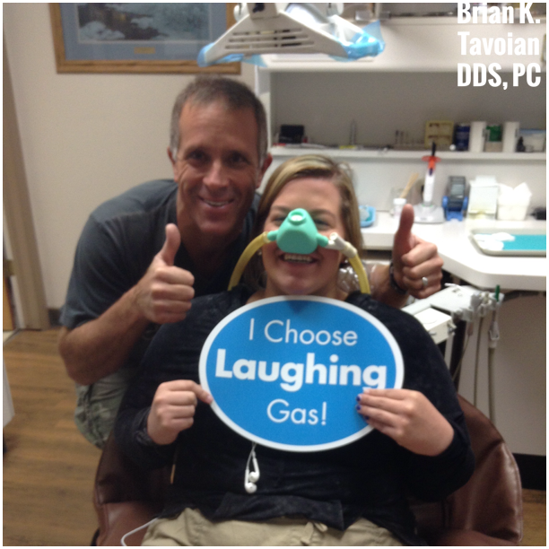 Dr. Tavoian and patient with Nitrous Oxide Mask on holding a sign reading "I Choose Laughing Gas!"
