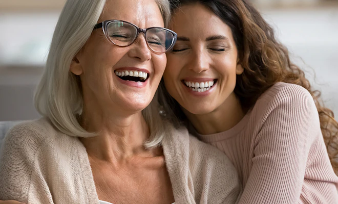 Mother and daughter laughing together and showing off their smiles
