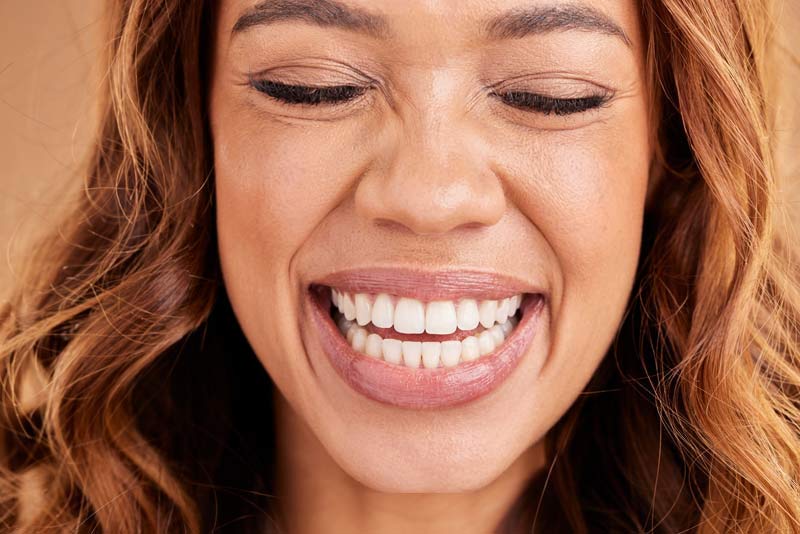Smiling woman with eyes closed showing bright white teeth in close-up portrait