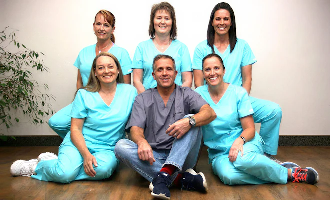 Dr. Tavoian sitting with his dental team in matching scrubs at their Cedar City office