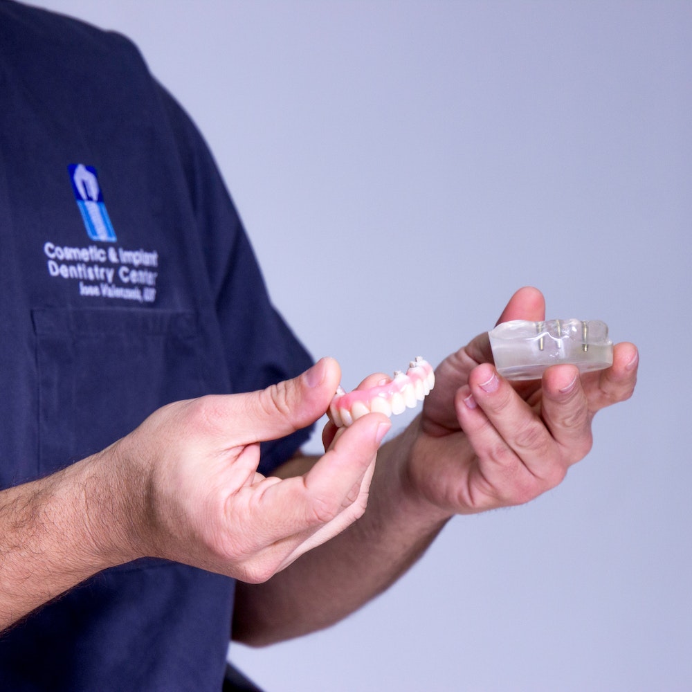 Dr. Valenzuela holding teeth models