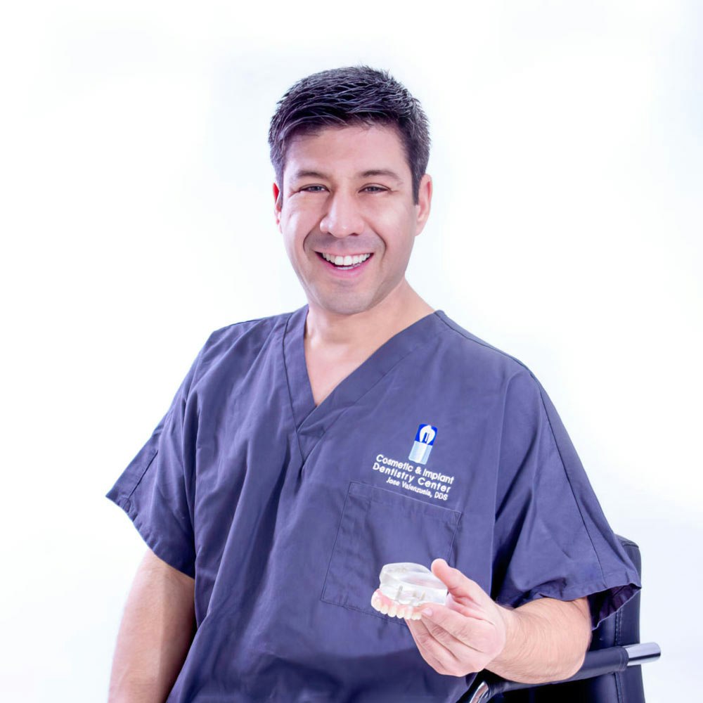 Dentist Jose Valenzuela, Jr holding a denture