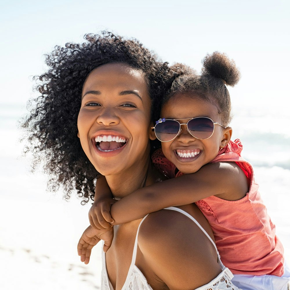 Smiling mother after tooth extraction with her child at the beach