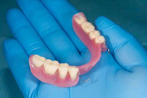 Gloved hand holding partial dentures