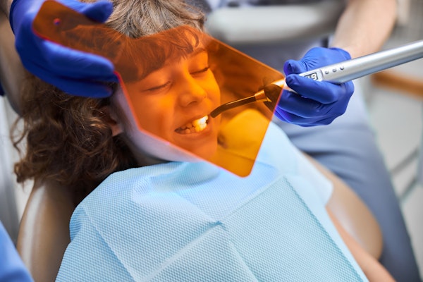 Dentist using curing light on boy