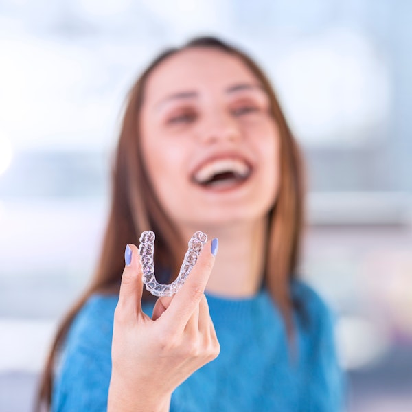 Girl holding out Invisalign aligner