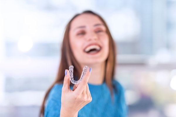 Girl holding out Invisalign aligner