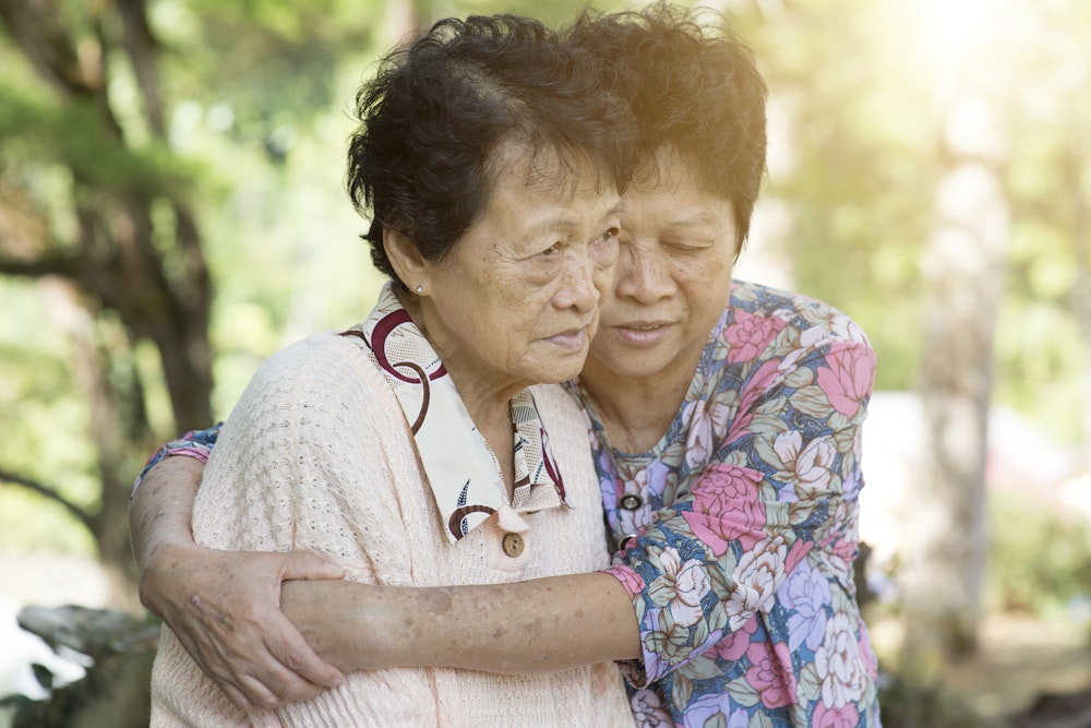 daughter hugging sad senior citezen mother