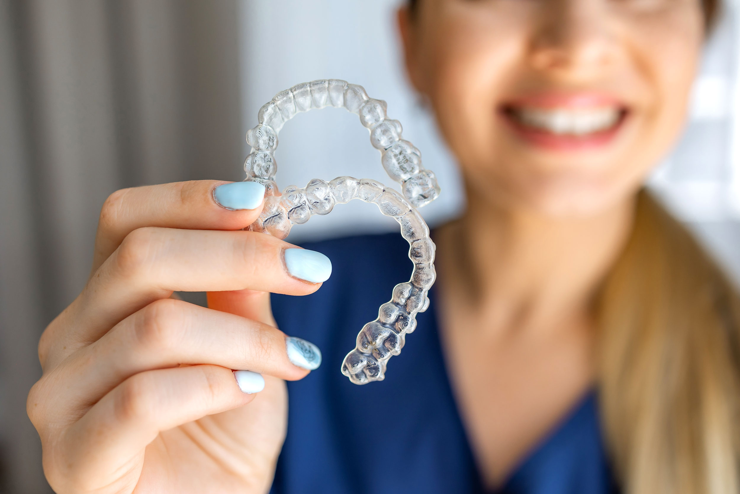 Smiling woman holding two Invisalign trays