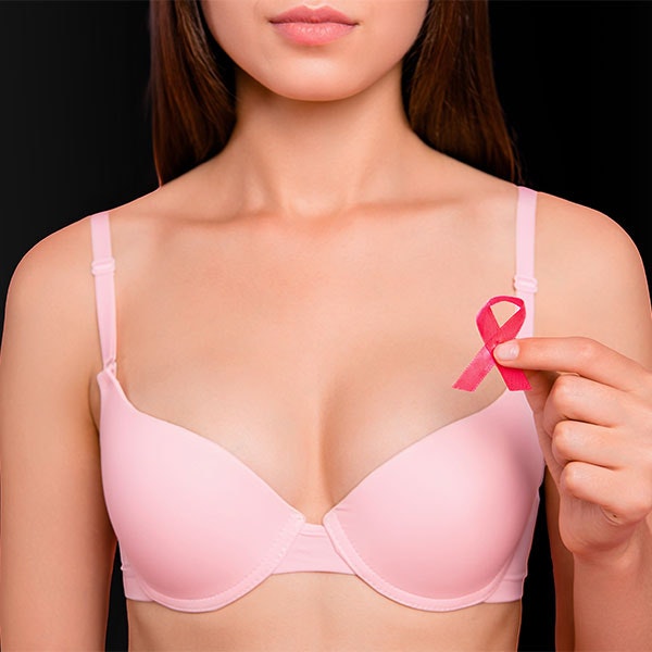 Close-up of woman in bra holding a breast cancer ribbon