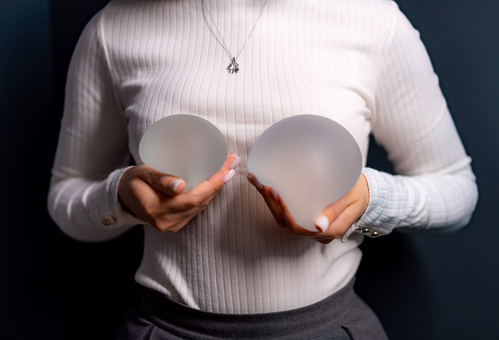 Woman holding up breast implants