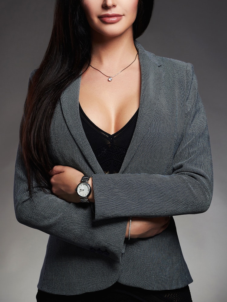 woman wearing grey business jacket and black shirt showcasing breast asymmetry surgery