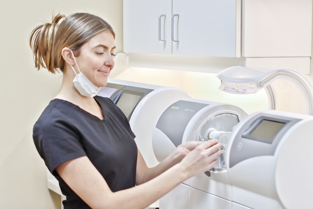Dental professional operating a CEREC machine to create same-day crowns in a modern dental office.