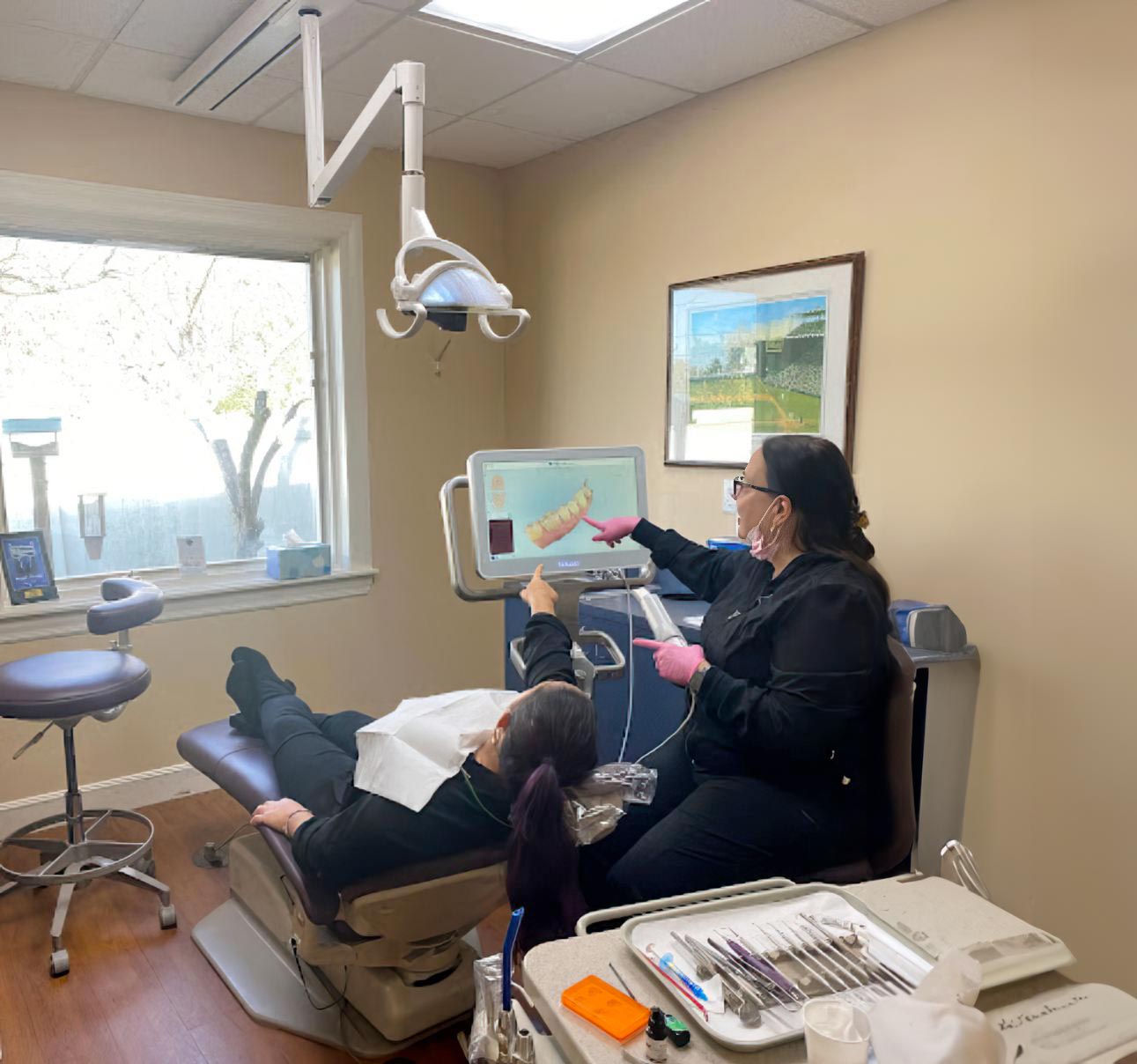 Hygienist looking at dental scans with patient